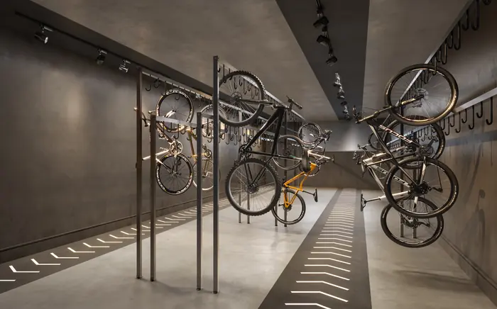 Bicicletário com bicicletas penduradas em ganchos ao longo das paredes de concreto