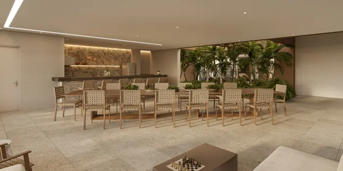 Espaço de churrasqueira com bancada e churrasqueira ao fundo e uma mesa comprida com doze cadeiras
