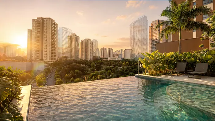 Piscina de borda infinita ao pôr do sol, com a lâmina d’água diante do parque e dos prédios da cidade