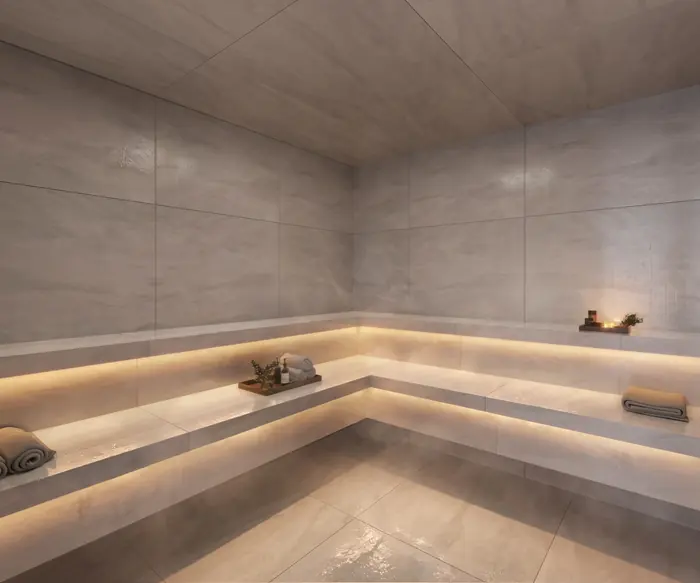 Sauna úmida revestida de pedra clara, com bancos em dois níveis e iluminação embutida sob eles